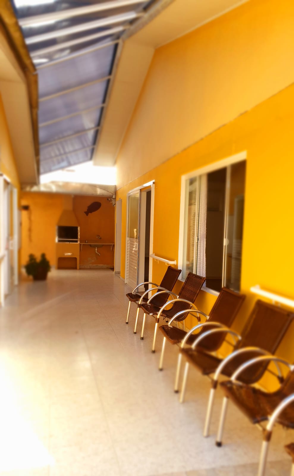 Corredor externo coberto com cadeiras e churrasqueira