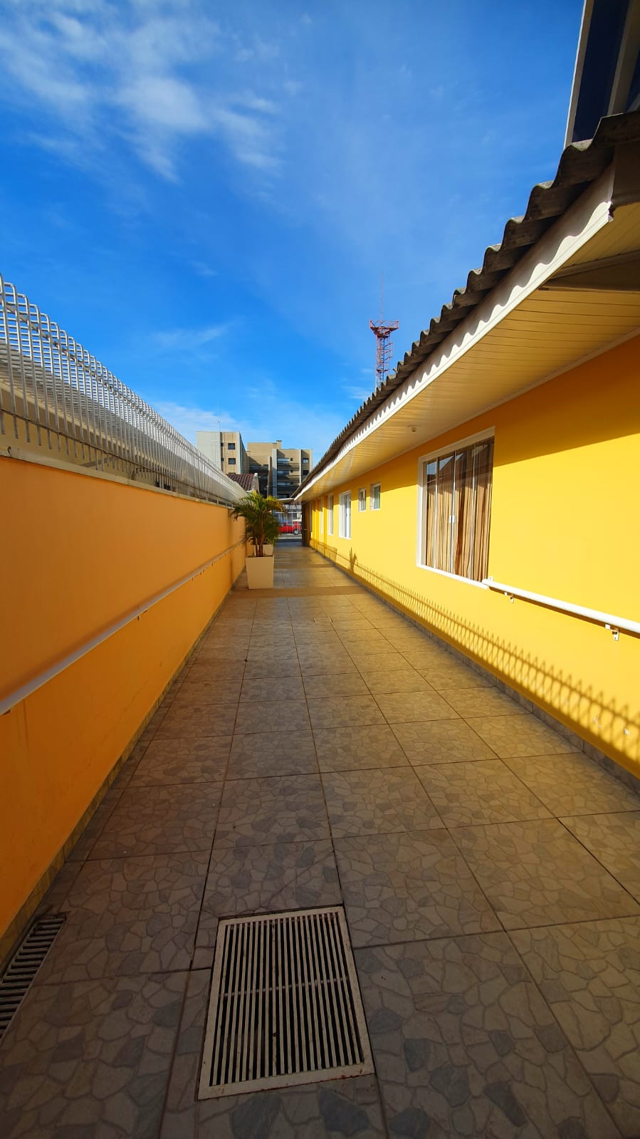 Passagem externa ampla entre os pavilhões da casa