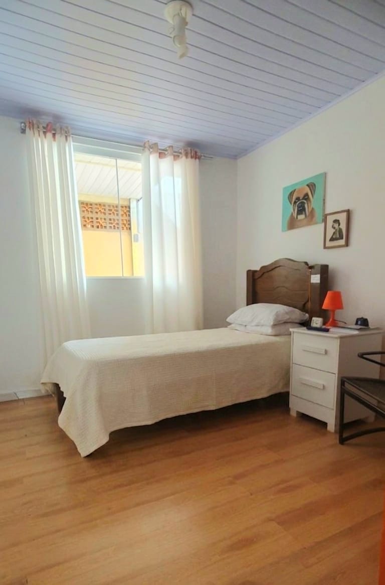 Quarto individual claro com cama de solteiro e decoração acolhedora