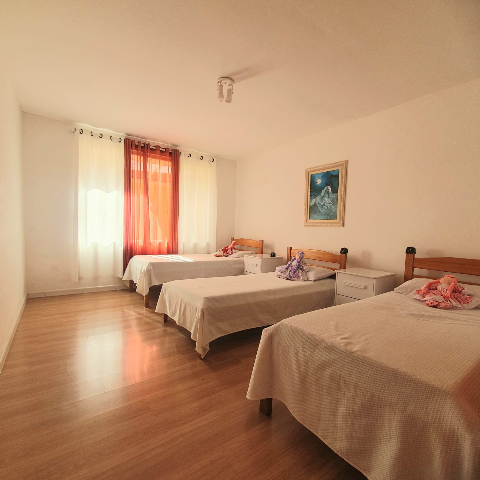 Quarto triplo com camas individuais, cortinas e obra de arte na parede