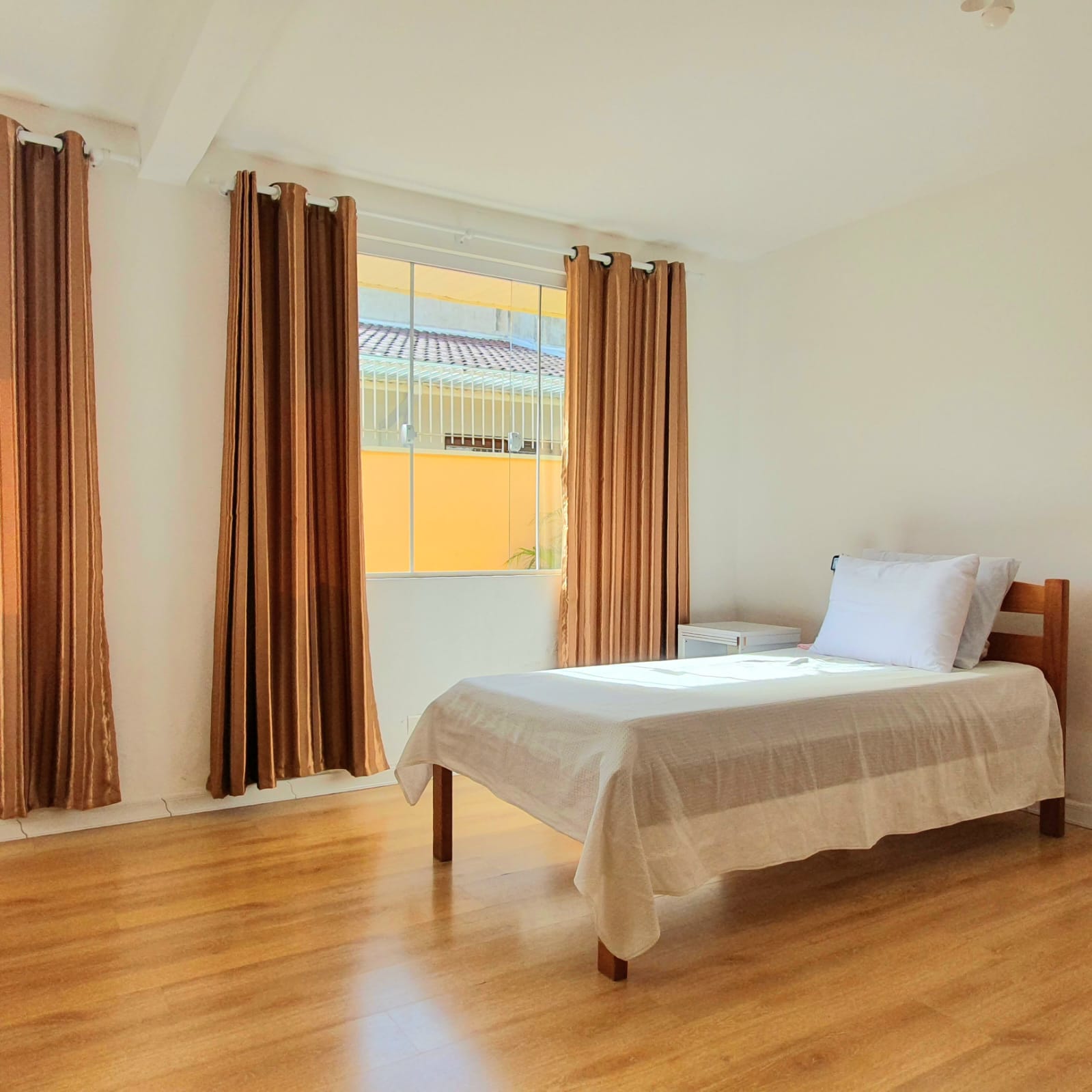 Quarto espaçoso com cama de solteiro e cortinas amplas